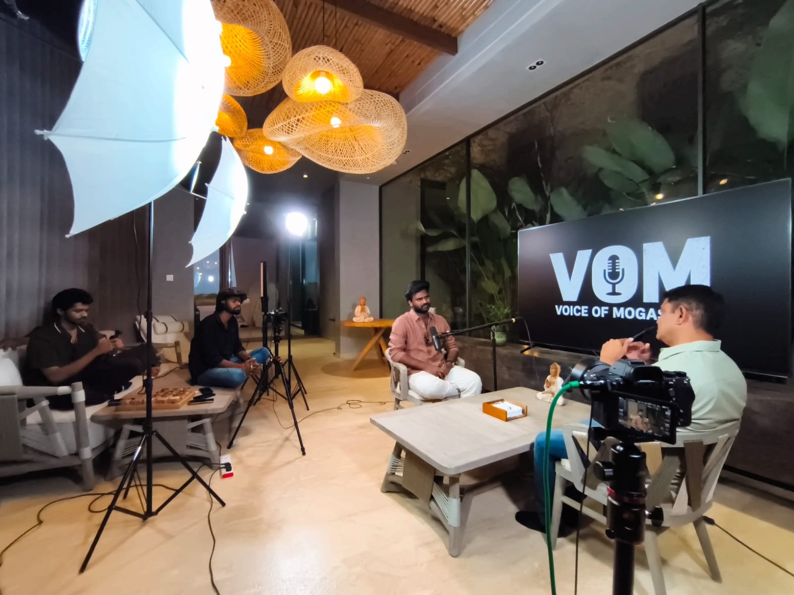 Epitome crew filming a podcast on location, with lights and cameras set up in a living room